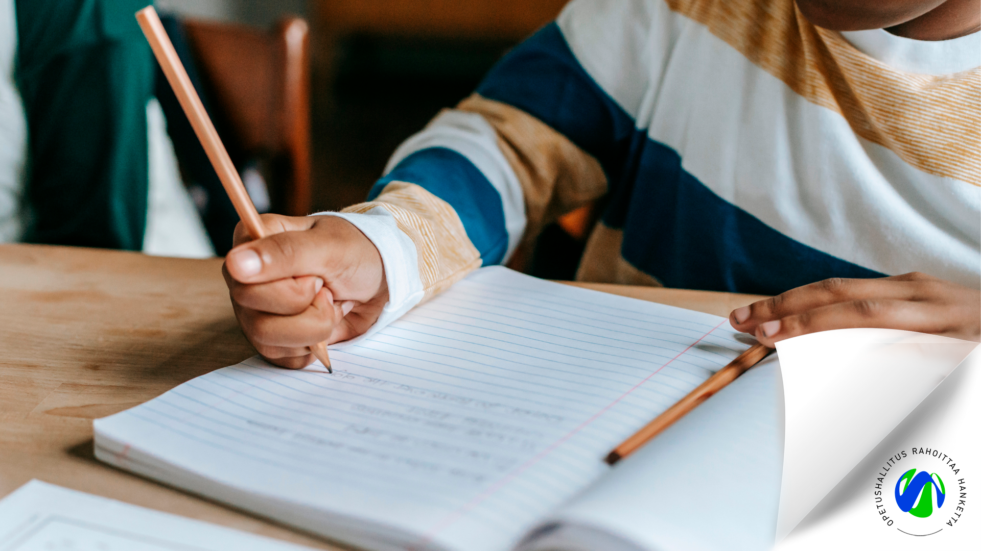 Lapsi kirjoittaa vihkoon lyijykynällä. OPH rahoittaa hanketta -logo alanurkassa.